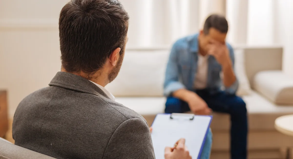 Psicólogo tomando notas durante una sesión con un paciente